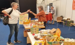 Hilde Delhey, aus der Steuerungsgruppe Fairtrade Landkreis MKK, eine Geschmacksprobe aus fairen Mangos an eine Messebesucherin zum Verkosten
