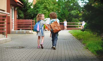zwei Kinder die in die Schule laufen
