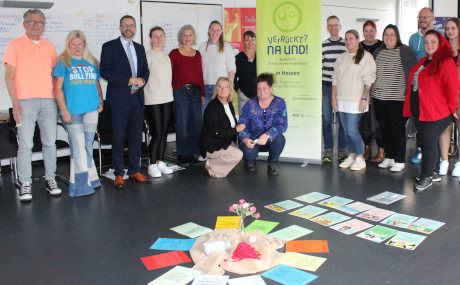 Das Team des Amts für Gesundheit und Gefahrenabwehr um Amtsleiter Dr. Wolfgang Lenz (links), Schirmherr Landrat Thorsten Stolz (Dritter von links) sowie Iris Jander und Dr. Simone Karau (kniend von links) hatten im Jahr 2025 Expertinnen und Experten im Main-Kinzig-Forum für das Präventionsprogramm „Verrückt? Na und! – Seelisch fit in der Schule“ ausgebildet und auf die „Schultage“ vorbereitet.