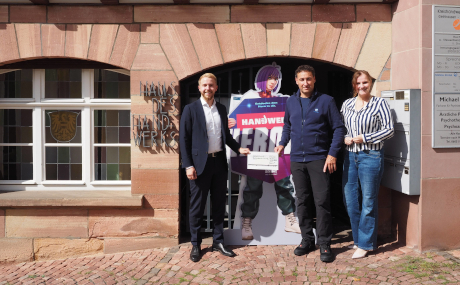 Erster Kreisbeigeordneter Jannik Marquart (links) übergibt Anett Kuykendall, Geschäftsführerin der Kreishandwerkerschaft Gelnhausen-Schlüchtern, und Stefan Maul, Ausbildungsleiter der Bildungszentrum Bau Osthessen, Stefan Maul, den Förderbescheid für die BBO.